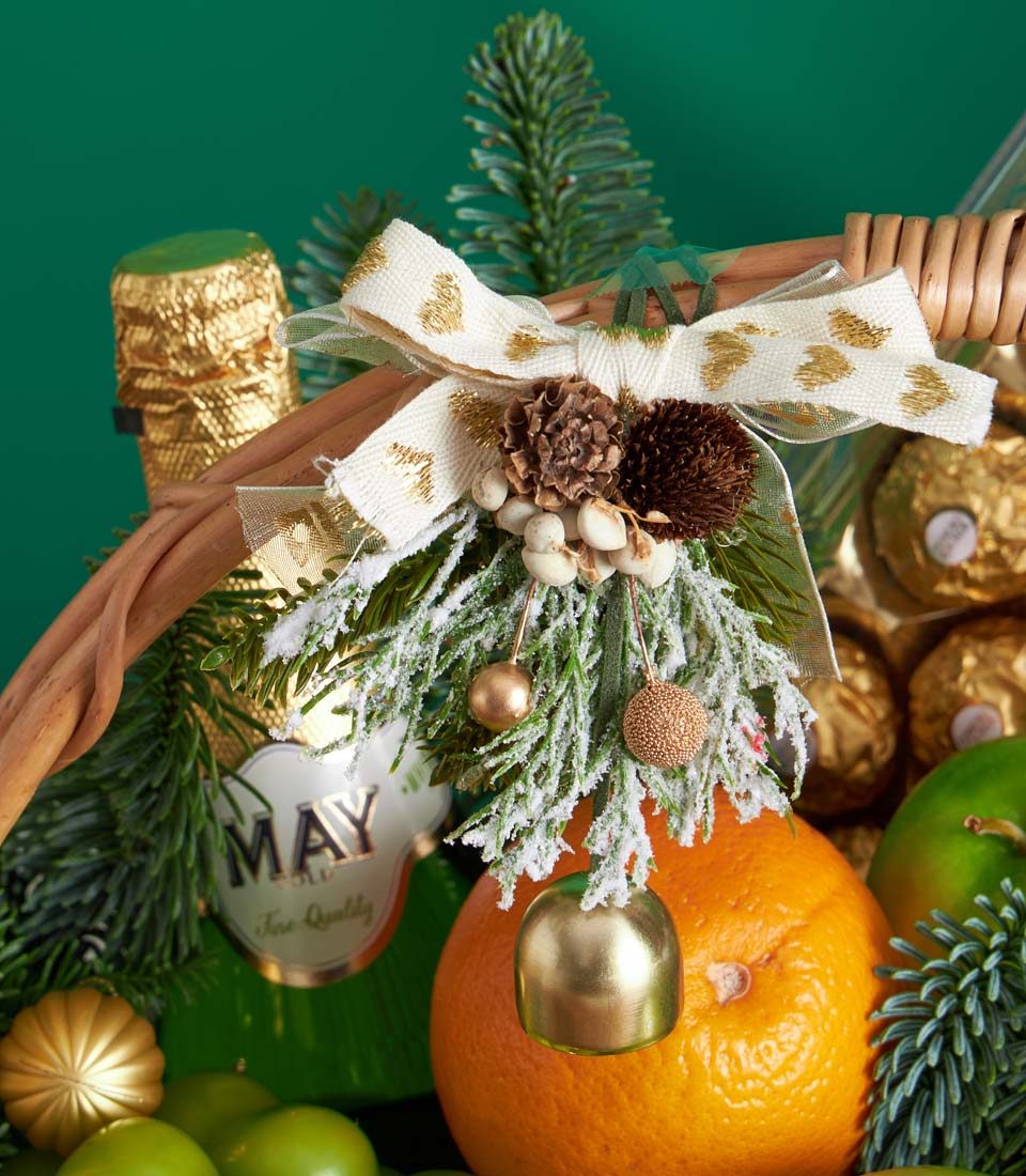 Festive Christmas fruit basket with champagne, fresh citrus, chocolates, and frosted evergreen ornament decoration