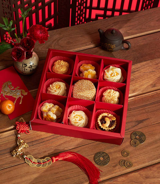 Classic Chinese New Year pastry assortment in red gift box with gold ingot and floral designs, accompanied by red envelope