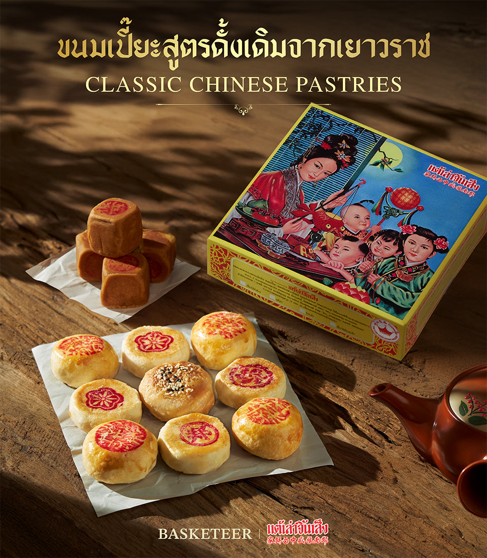 Golden Chinese New Year pastry gift set with red-stamped mooncakes, sesame treats, and traditional teapot on rustic wood