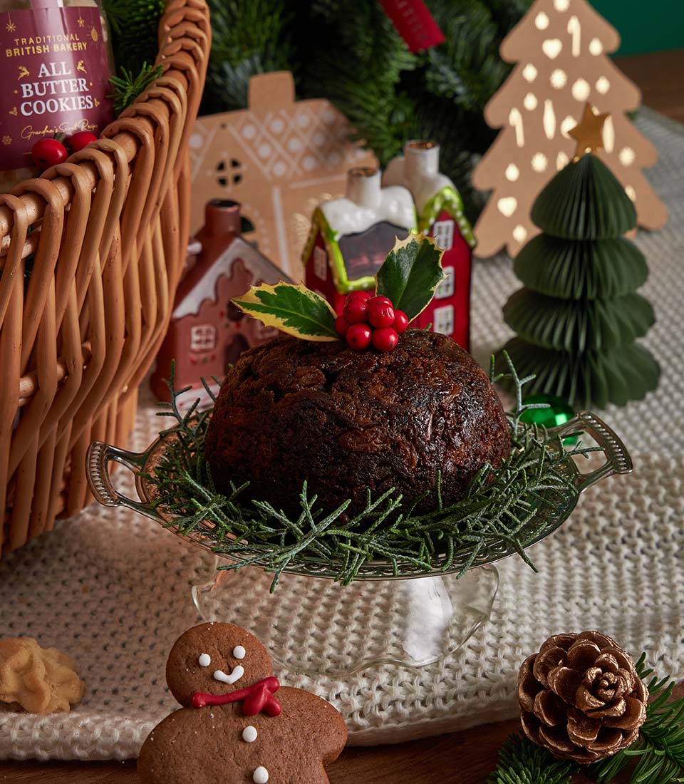 Festive Christmas hamper with traditional British pudding, butter cookies, gingerbread treats, and holiday decorations on