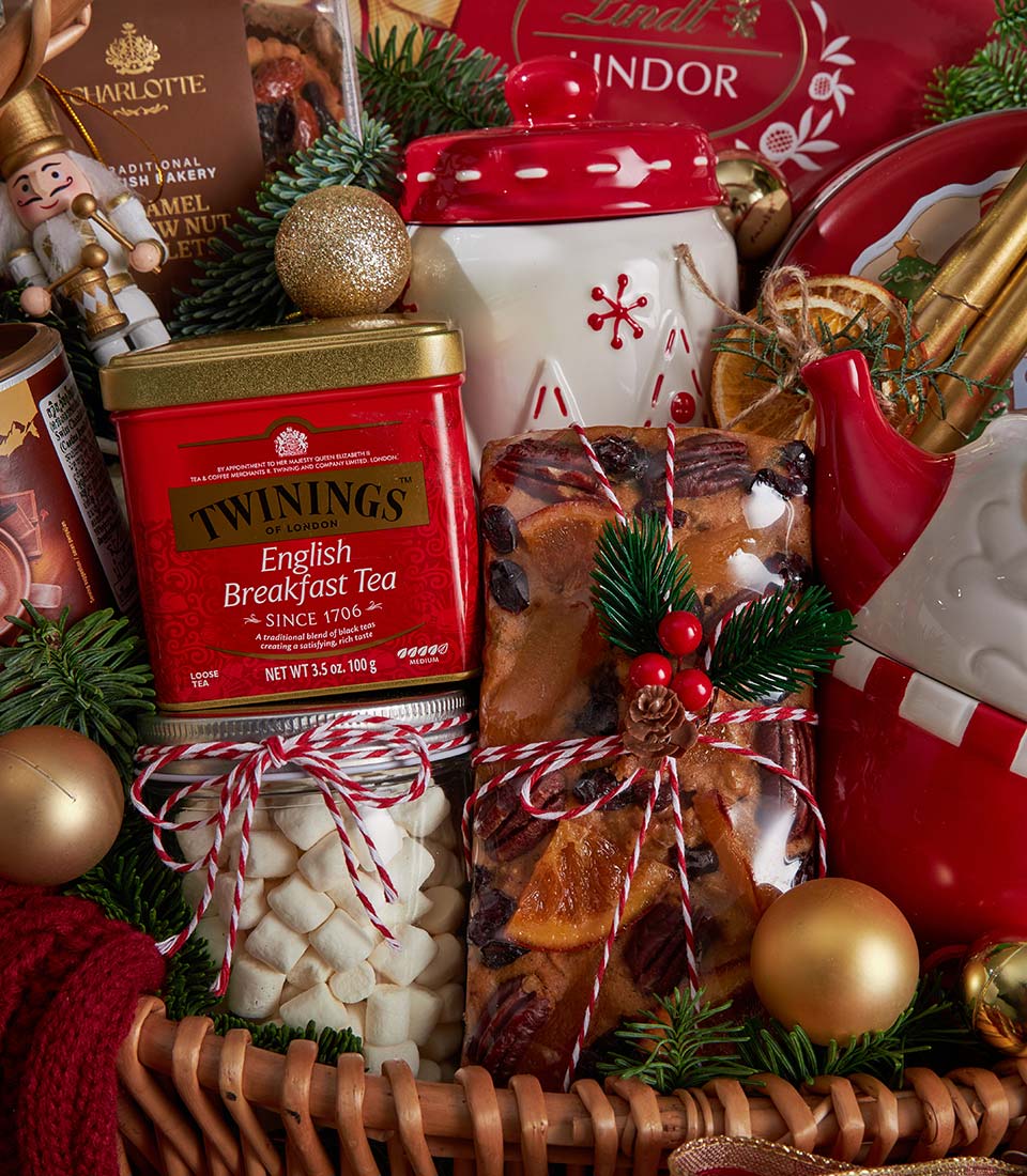 Luxury Christmas tea, chocolate and fruitcake gift basket with festive gold ornaments and red wicker presentation