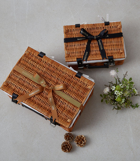Wicker picnic baskets with black leather straps and ribbon bows, paired with white flowers and gold accents