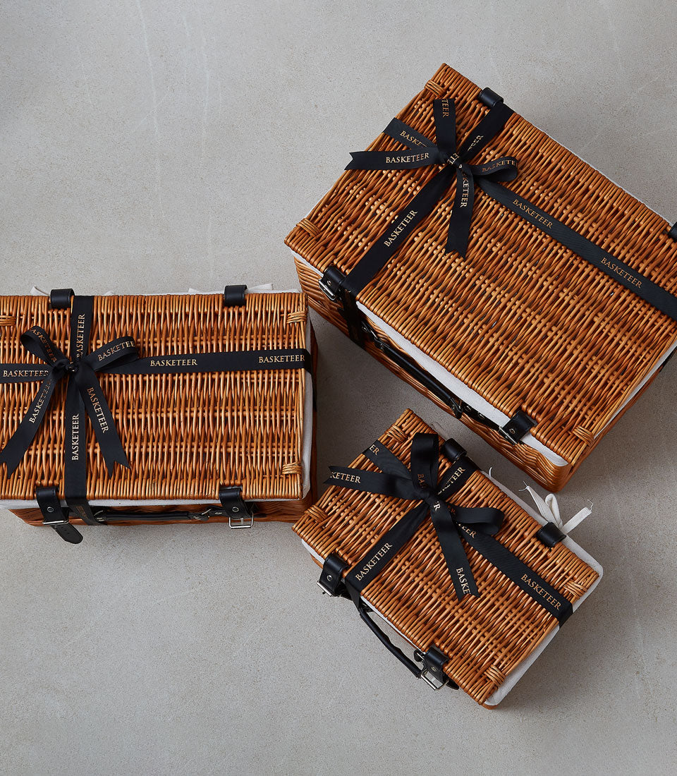 Woven wicker gift baskets with leather straps and Basketeer ribbon, luxury gourmet hamper collection