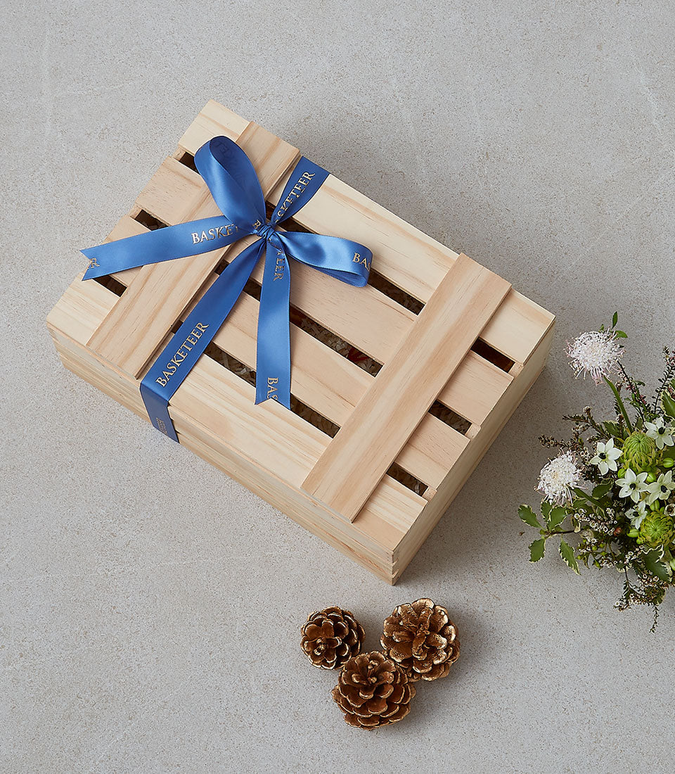 Deluxe wooden gourmet gift hamper with royal blue ribbon and fresh white flowers