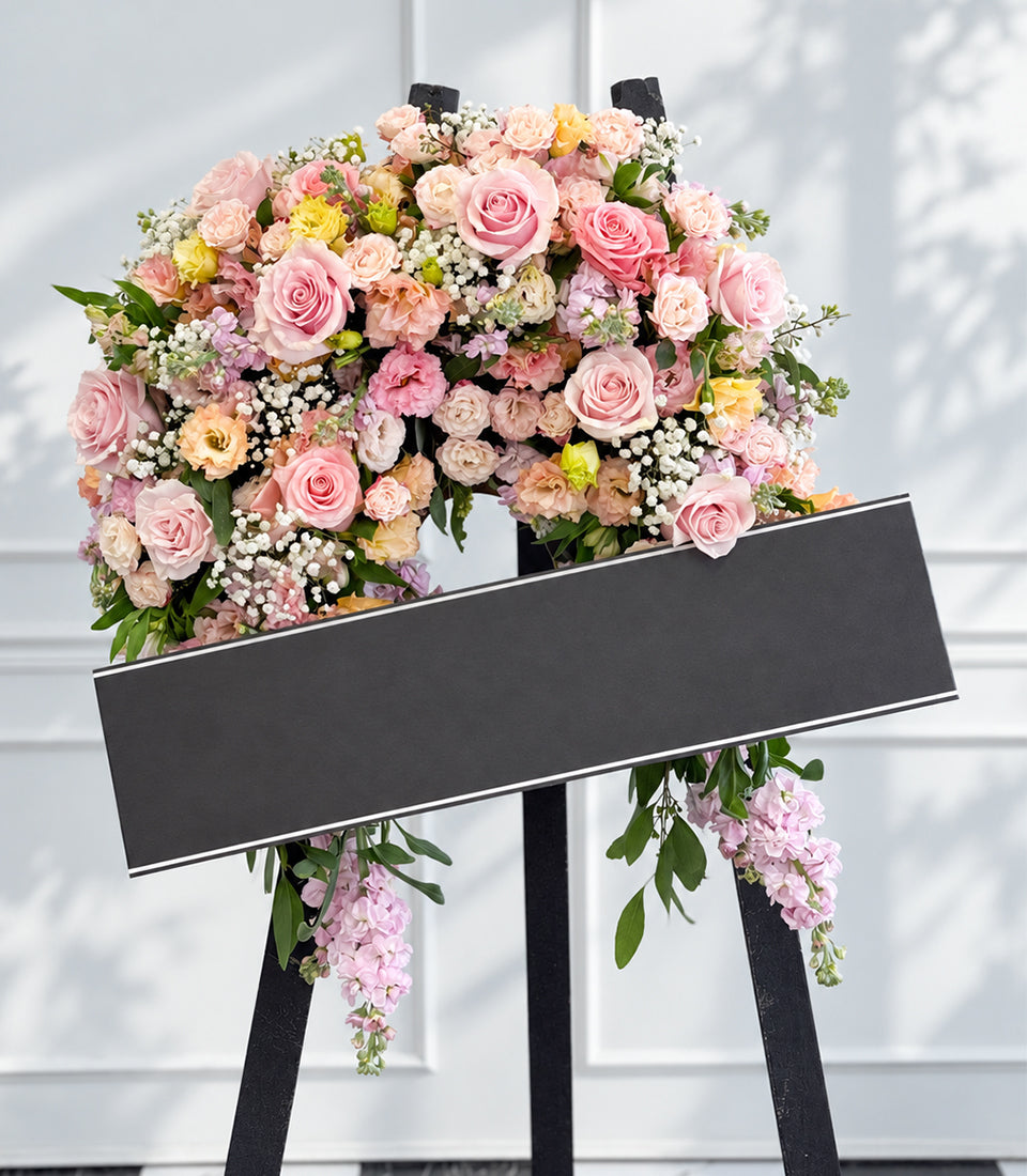 An elegant crescent wreath arrangement from Flowers by Basketeer, featuring premium pink