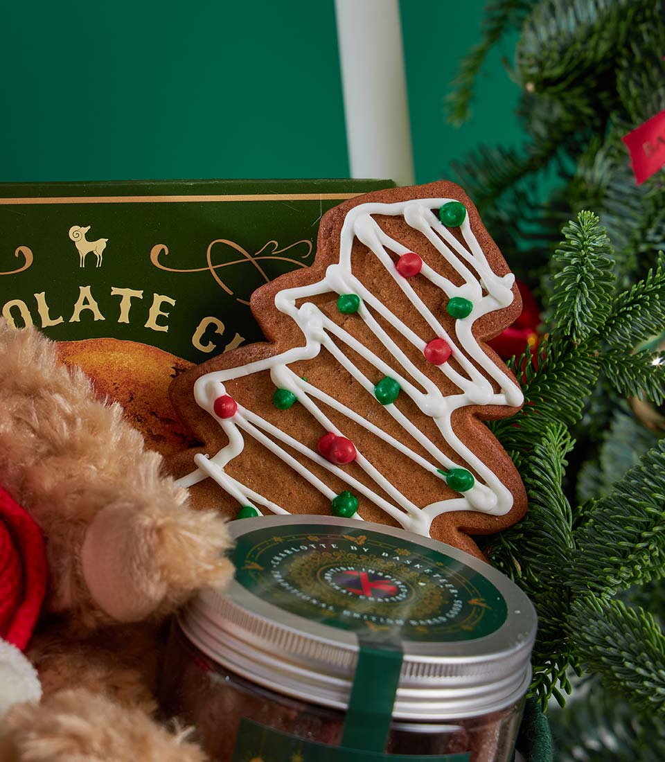 Festive Christmas gift box with gingerbread tree cookie, teddy bear in Santa hat, and Charlotte Bakery treats