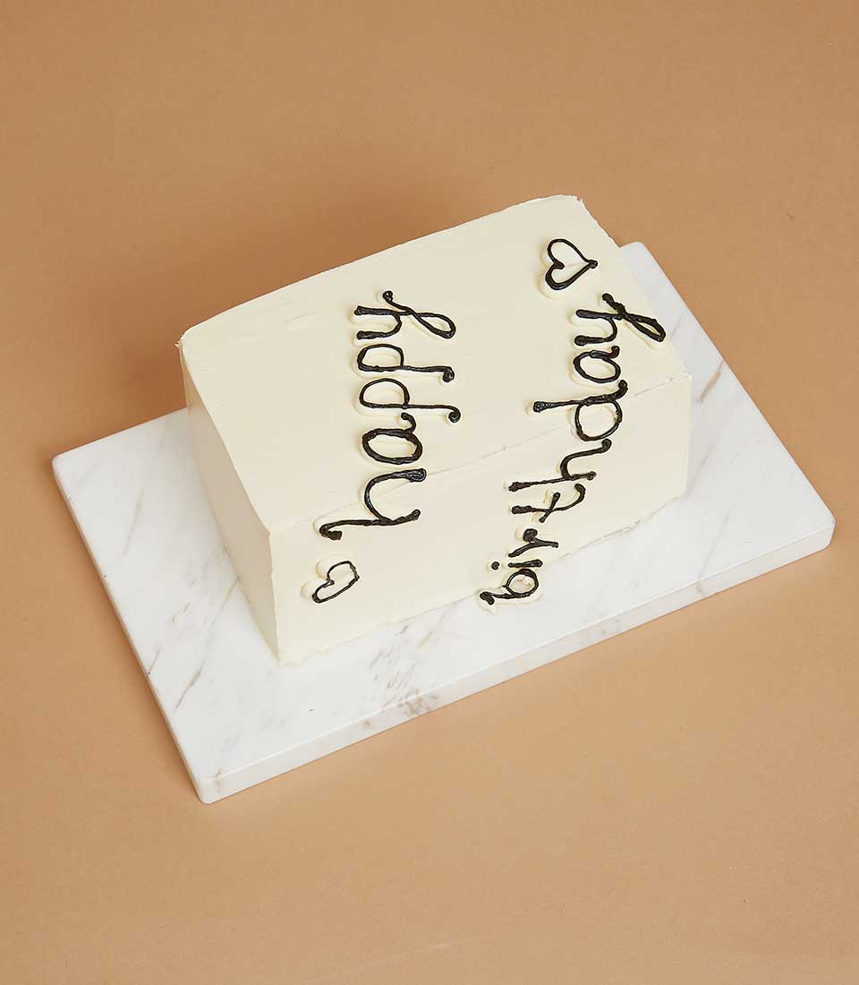 Vanilla strawberry jam layer cake with black cursive "happy birthday" message and heart details on white frosting