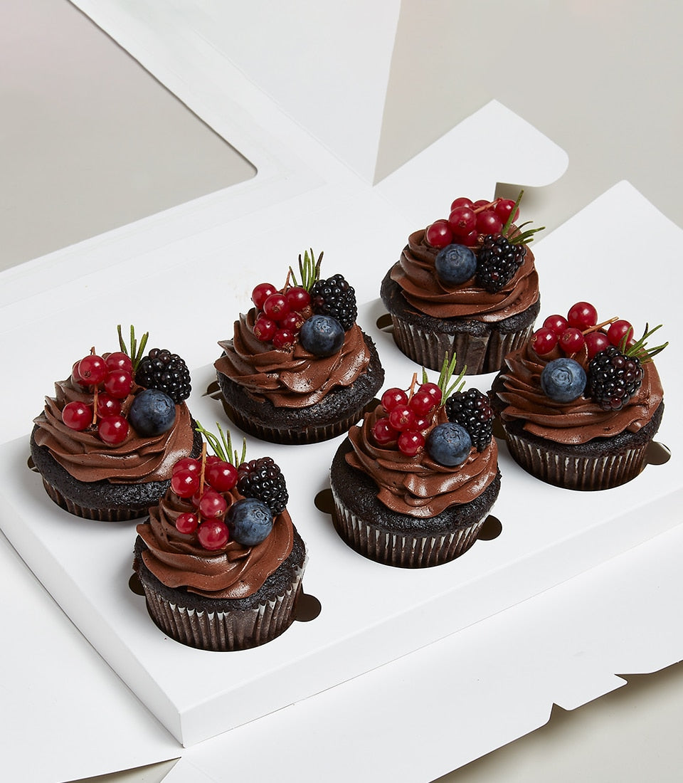 Six chocolate cupcakes with fresh berries and dark frosting in white gift box compartments