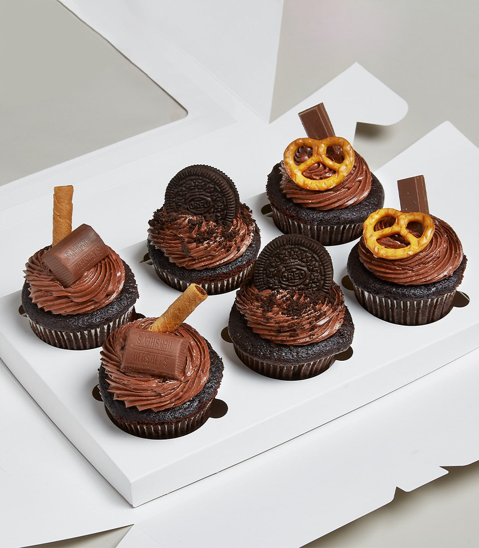 Assorted chocolate cupcakes with pretzel, Oreo, and candy toppings in white gift box