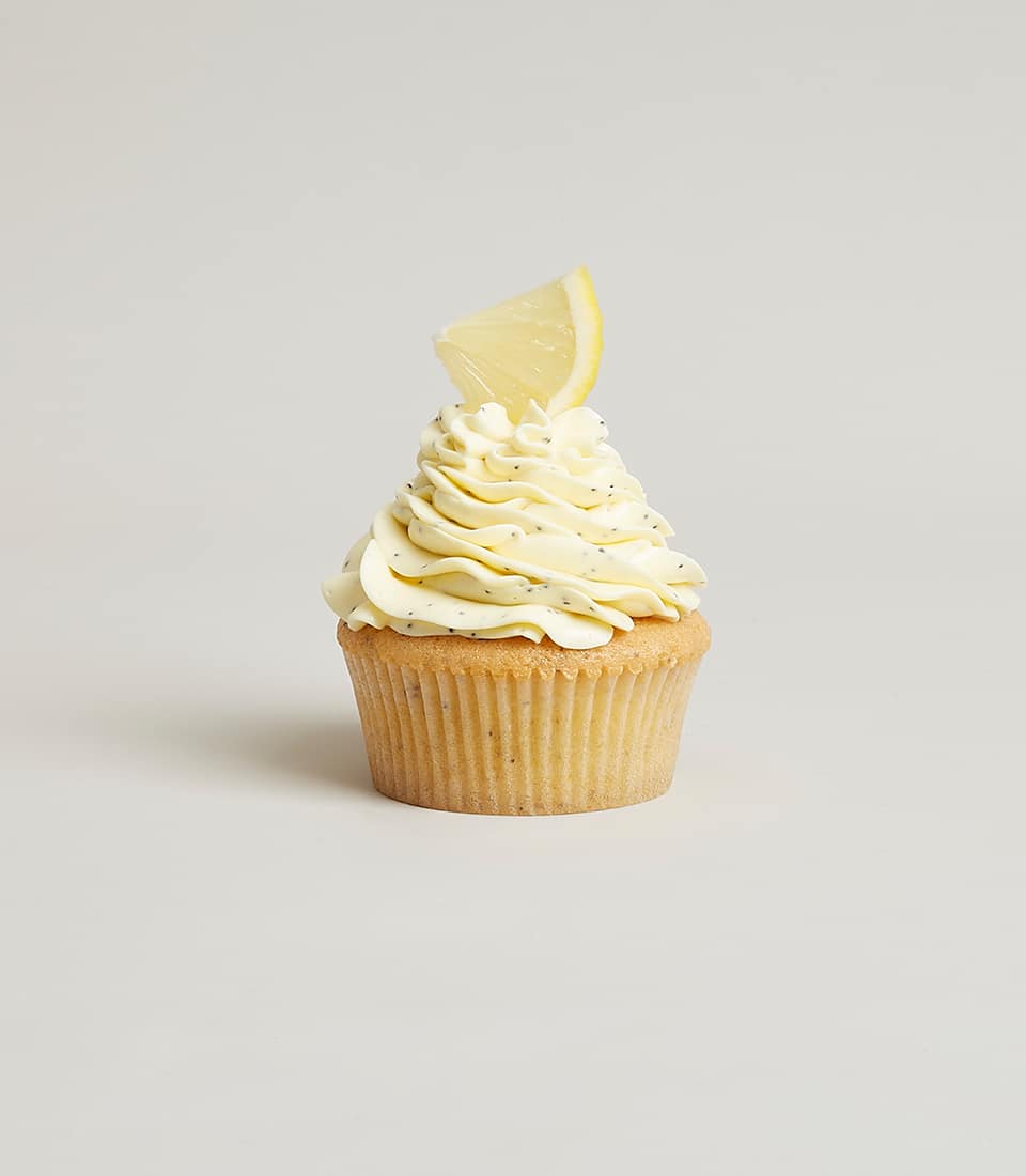 Lemon poppy seed cupcake with pale yellow frosting and fresh lemon slice