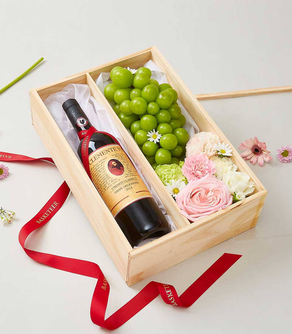 Deluxe wooden gift box with red wine, fresh roses, carnations, daisies, and green grapes with Basketeer ribbon