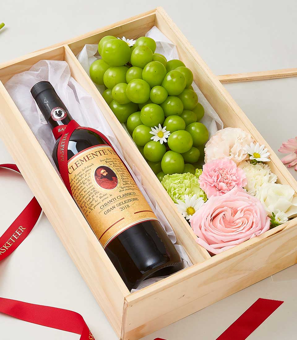 Wooden luxury gift box with Chianti Classico wine, fresh green grapes, pink roses, and white daisies