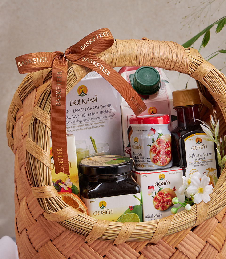 Woven straw gift basket filled with Doi Kham herbal wellness products including lemongrass drink, honey, and botanical