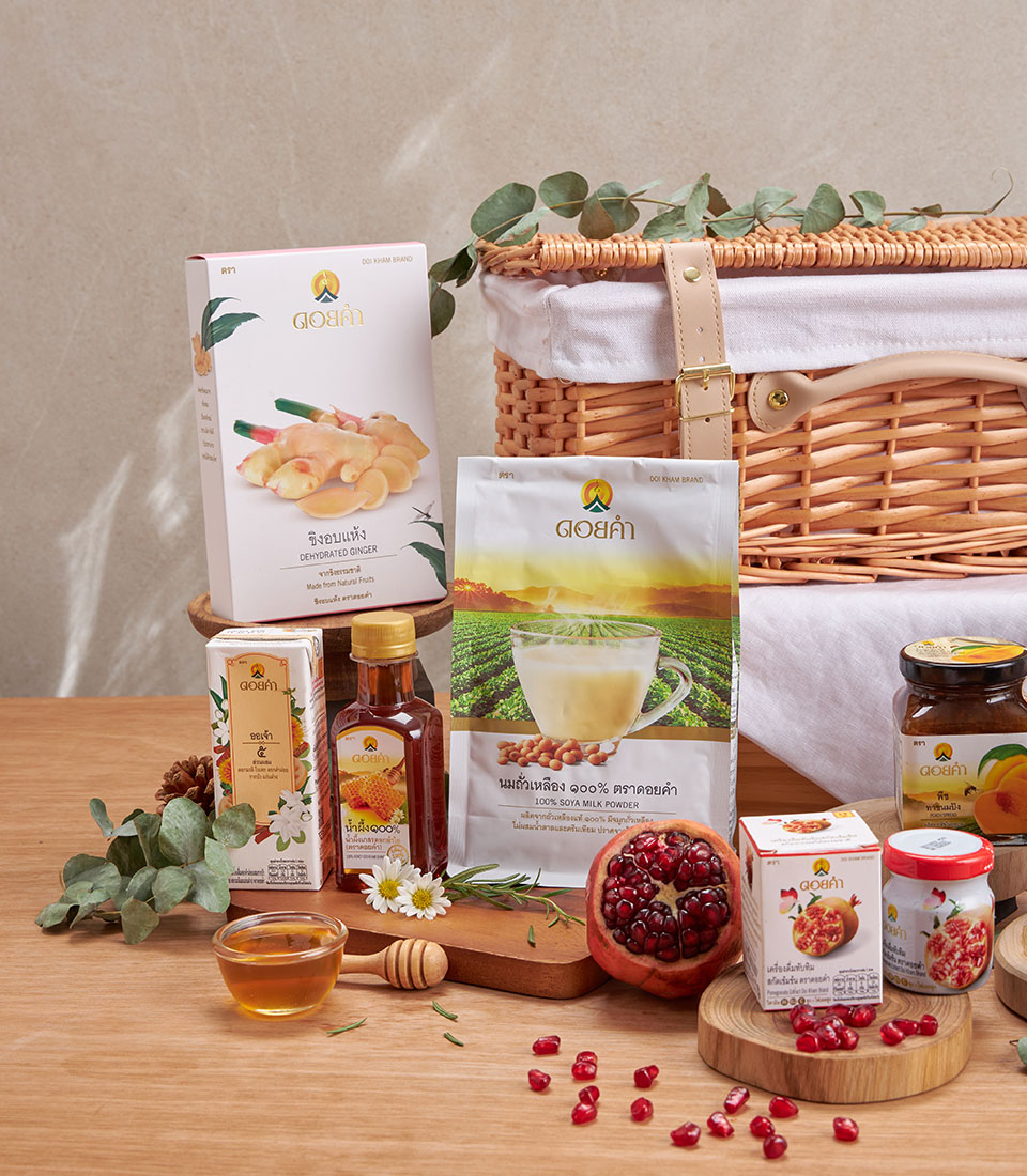 Doi Kham premium wellness gift basket with honey, herbal tea, pomegranate, and soya milk on natural wood surface