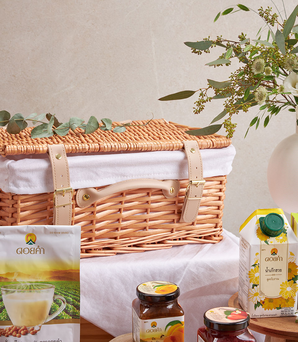 Premium wellness gift hamper with herbal tea, honey, fruit preserves, and fresh juice in wicker picnic basket