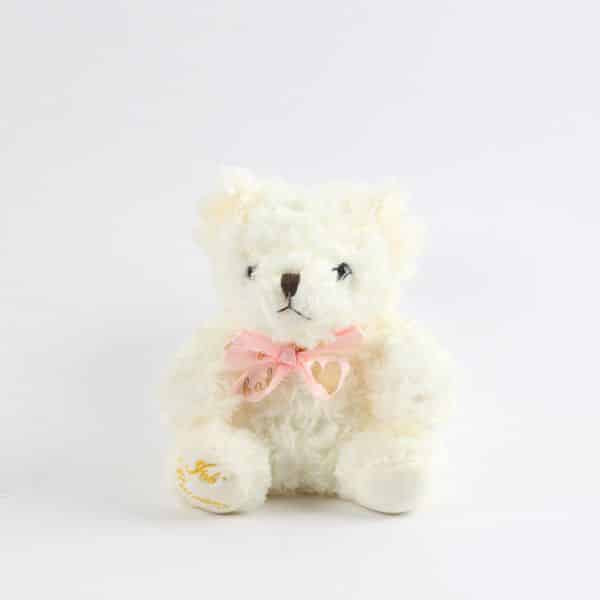 Cream plush teddy bear with pink satin bow and heart charm, perfect for gift hampers