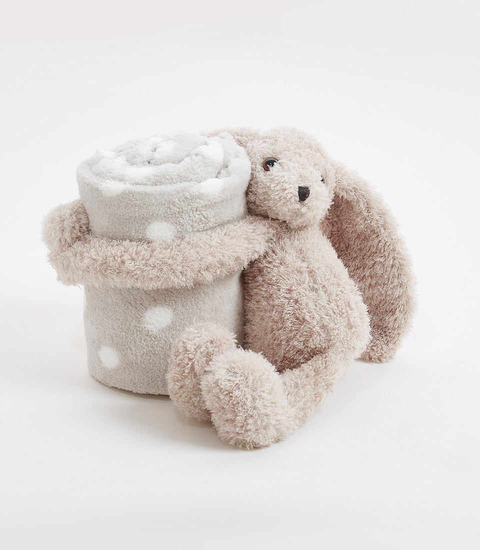 Soft beige plush bunny with floppy ears hugging polka dot baby blanket