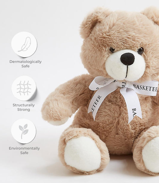 Tan plush teddy bear with black embroidered features and grosgrain ribbon bow, dermatologically safe soft toy