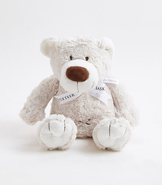 Plush beige teddy bear with dark brown nose and white bow ribbon, soft toy for babies and kids