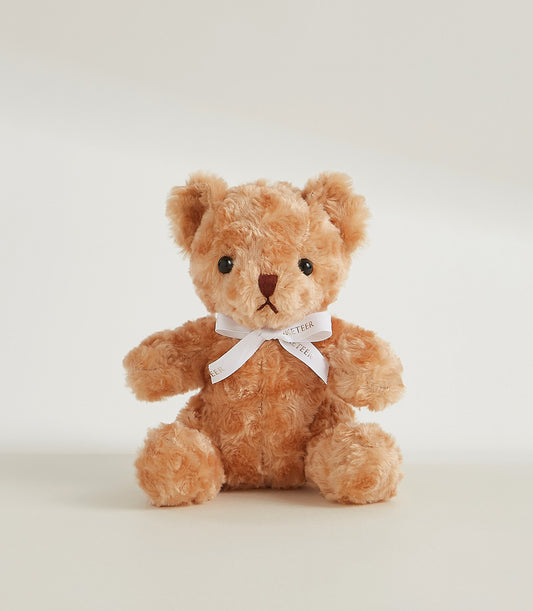 Soft plush amber teddy bear with white ribbon bow, perfect for gifting