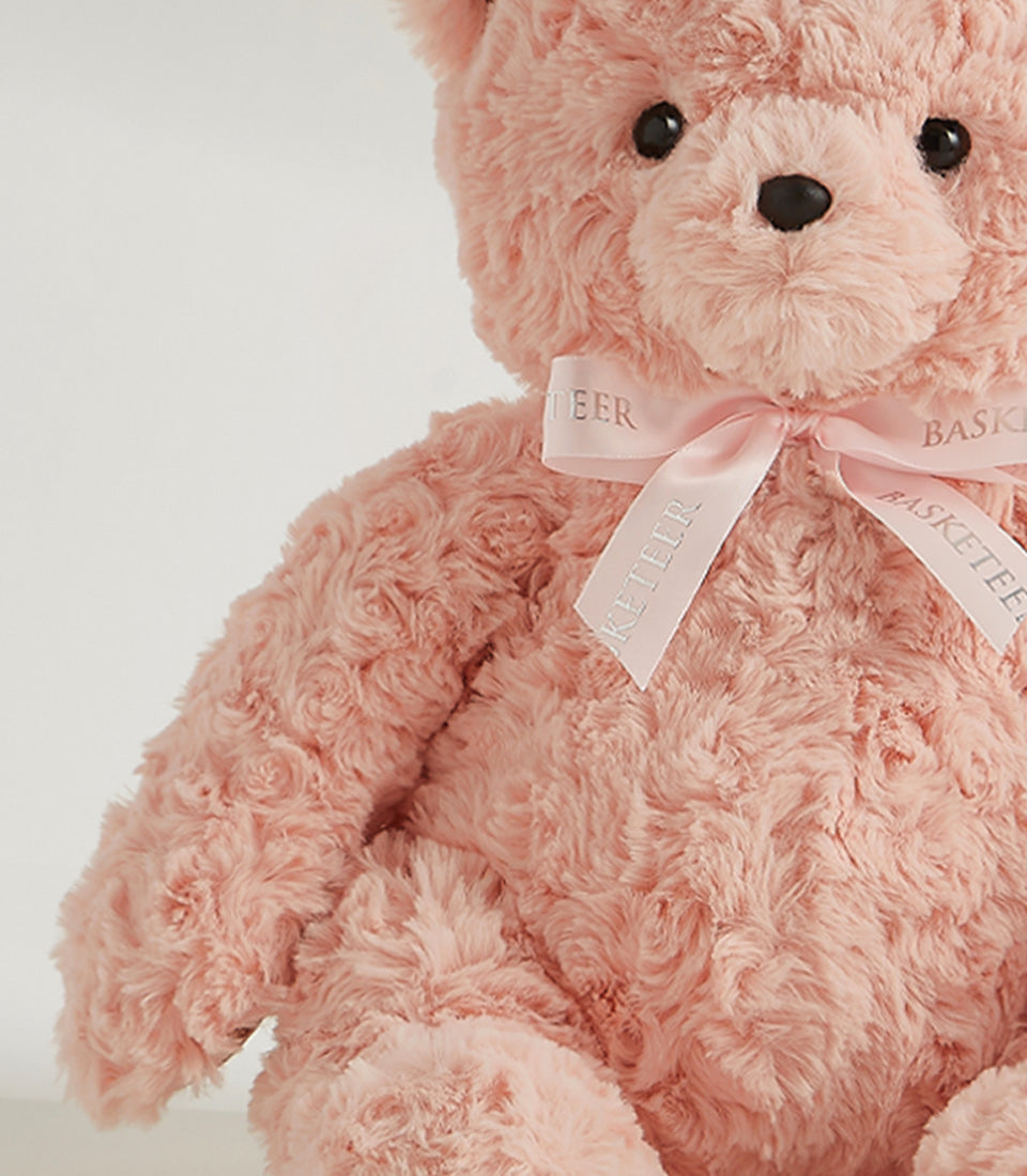 Soft pink plush teddy bear with curly fur and satin ribbon bow for gift giving