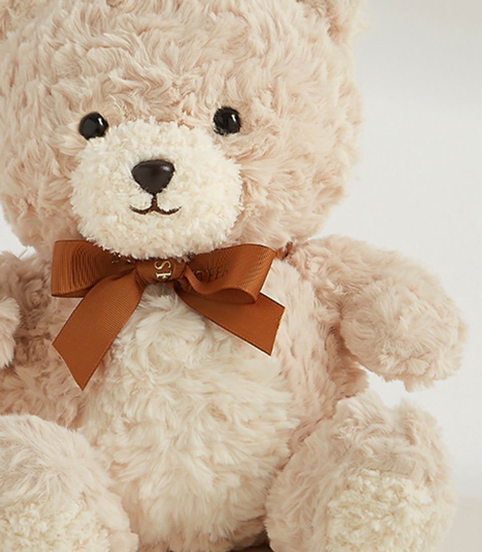 Soft caramel teddy bear with brown satin ribbon bow, perfect for gifting