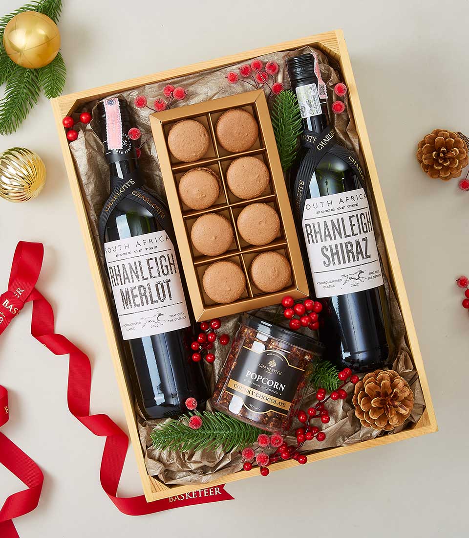 Luxury wine gift basket with Merlot and Shiraz, gourmet macarons, and chocolate popcorn in wooden crate