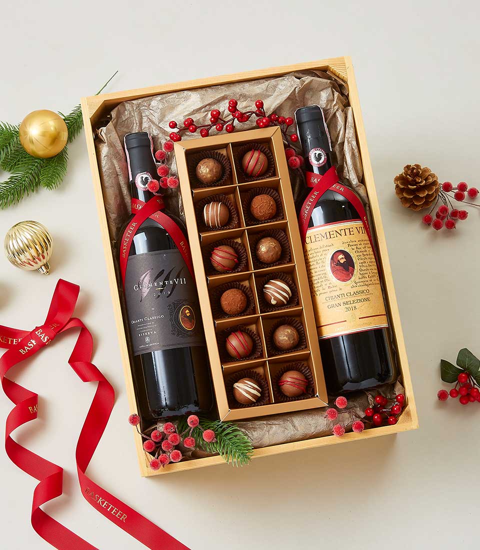 Premium wine and chocolate gift set in wooden crate with red wine, artisan chocolates, and festive berries