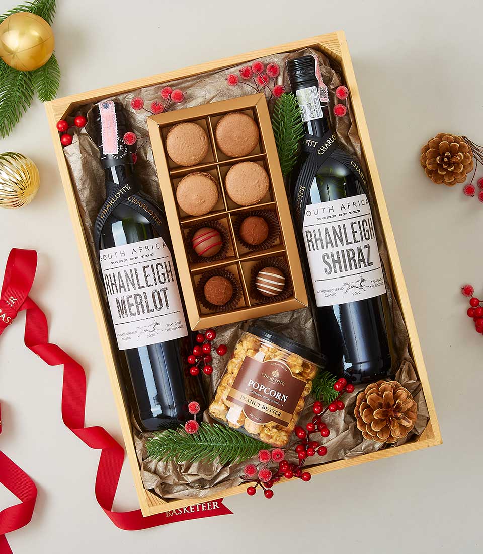 Rhanleigh wine gift box with Merlot and Shiraz, macarons, chocolates, and peanut butter popcorn in festive pine and berry