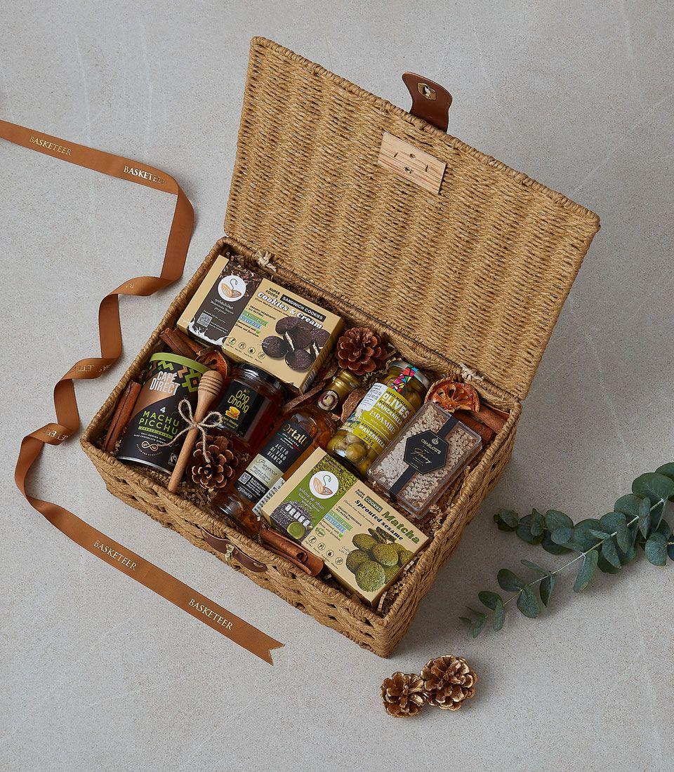 Woven wicker hamper filled with gourmet cookies, honey, coffee, olive oil, and olives for gifting