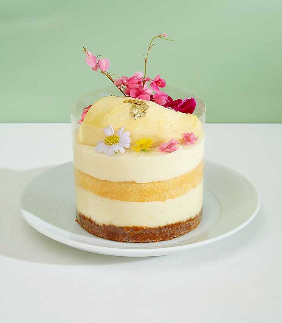 Mini durian layer cake with cream mousse, golden sponge, and edible gold leaf topping in clear container