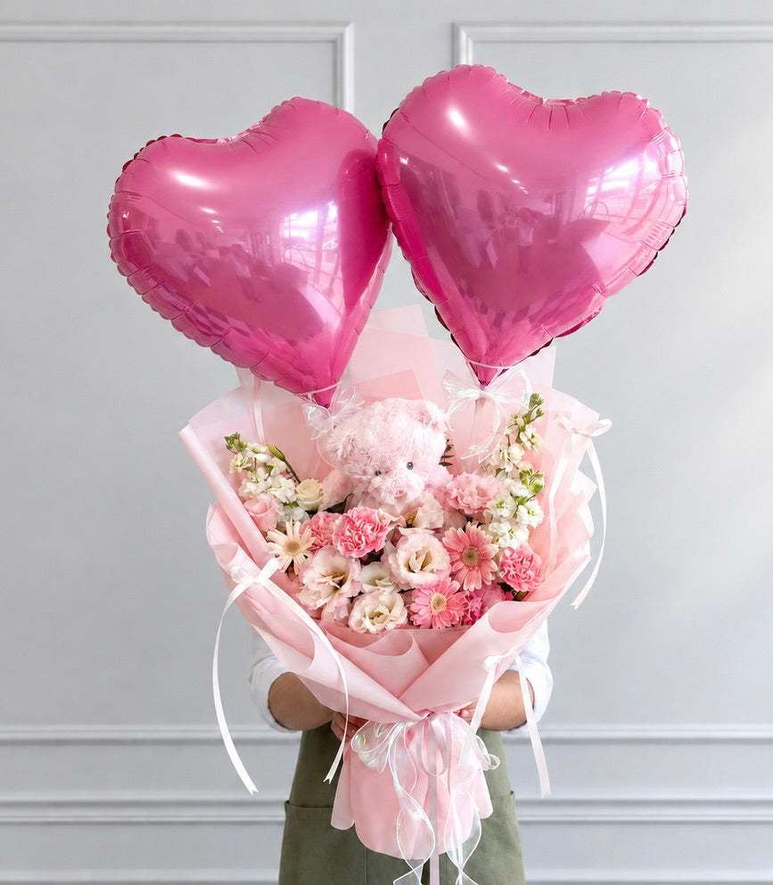 Front model-held view of pink teddy bear and heart balloon flower bouquet