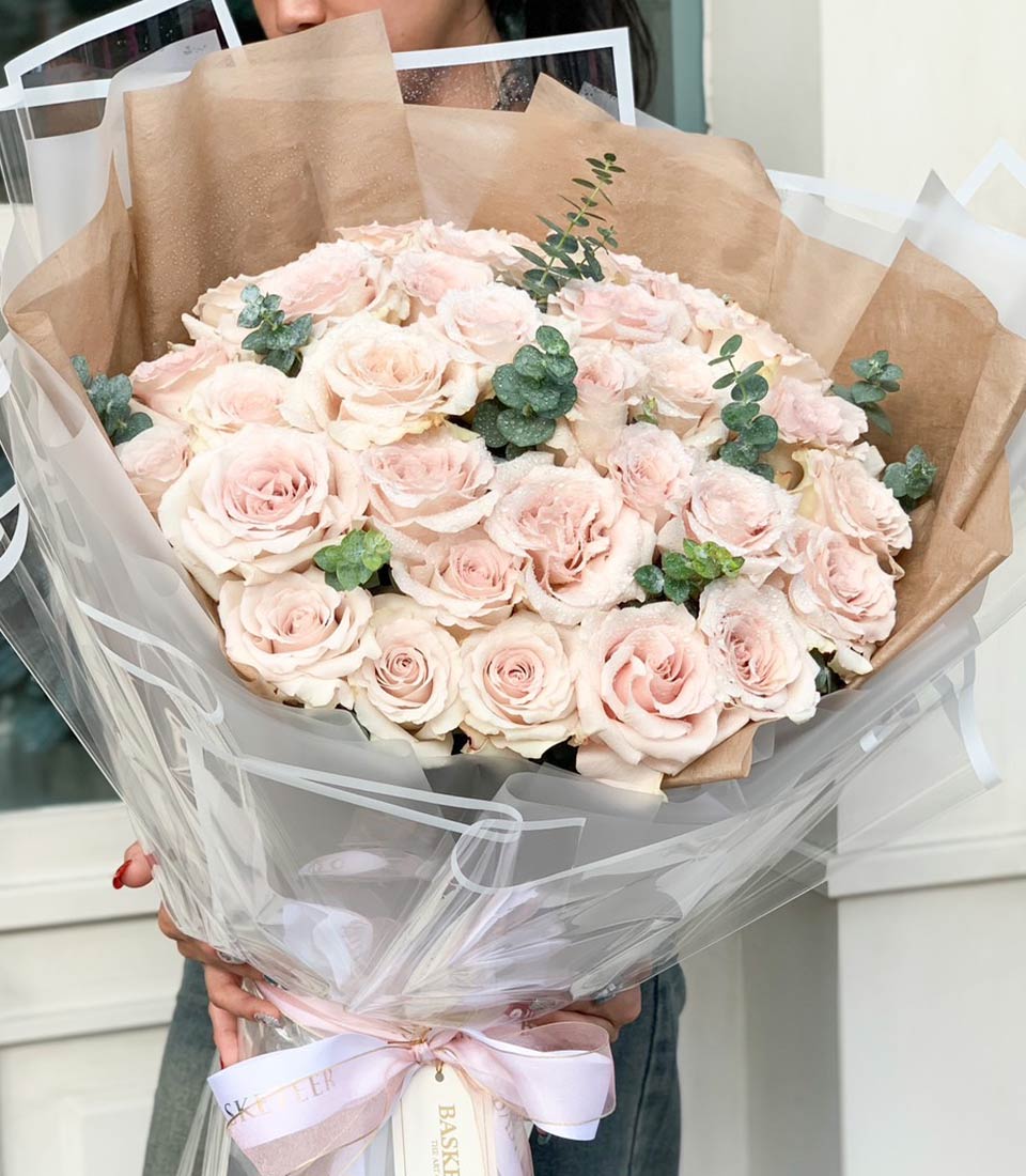 Large bouquet of fresh pink Mondial roses with eucalyptus, kraft paper wrap, and ribbon tie