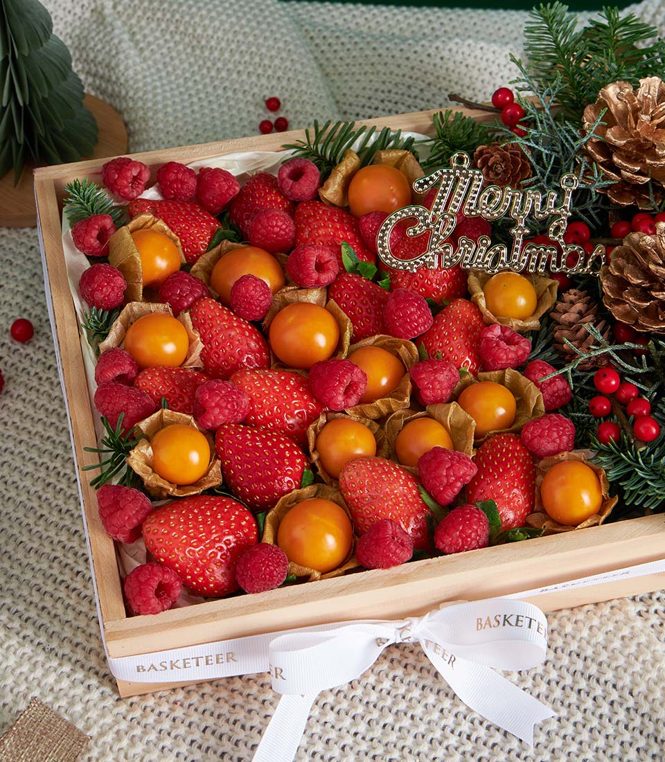 Festive strawberry and raspberry wooden gift box with ground cherries, pine sprigs, and holiday ribbon