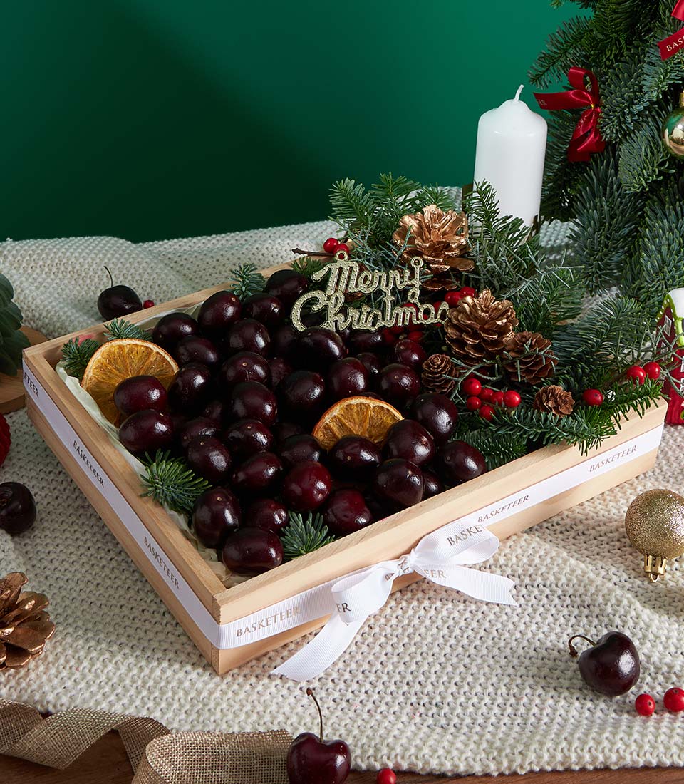 Premium dark cherry fruit gift box with dried citrus, evergreen and golden pinecones for Christmas