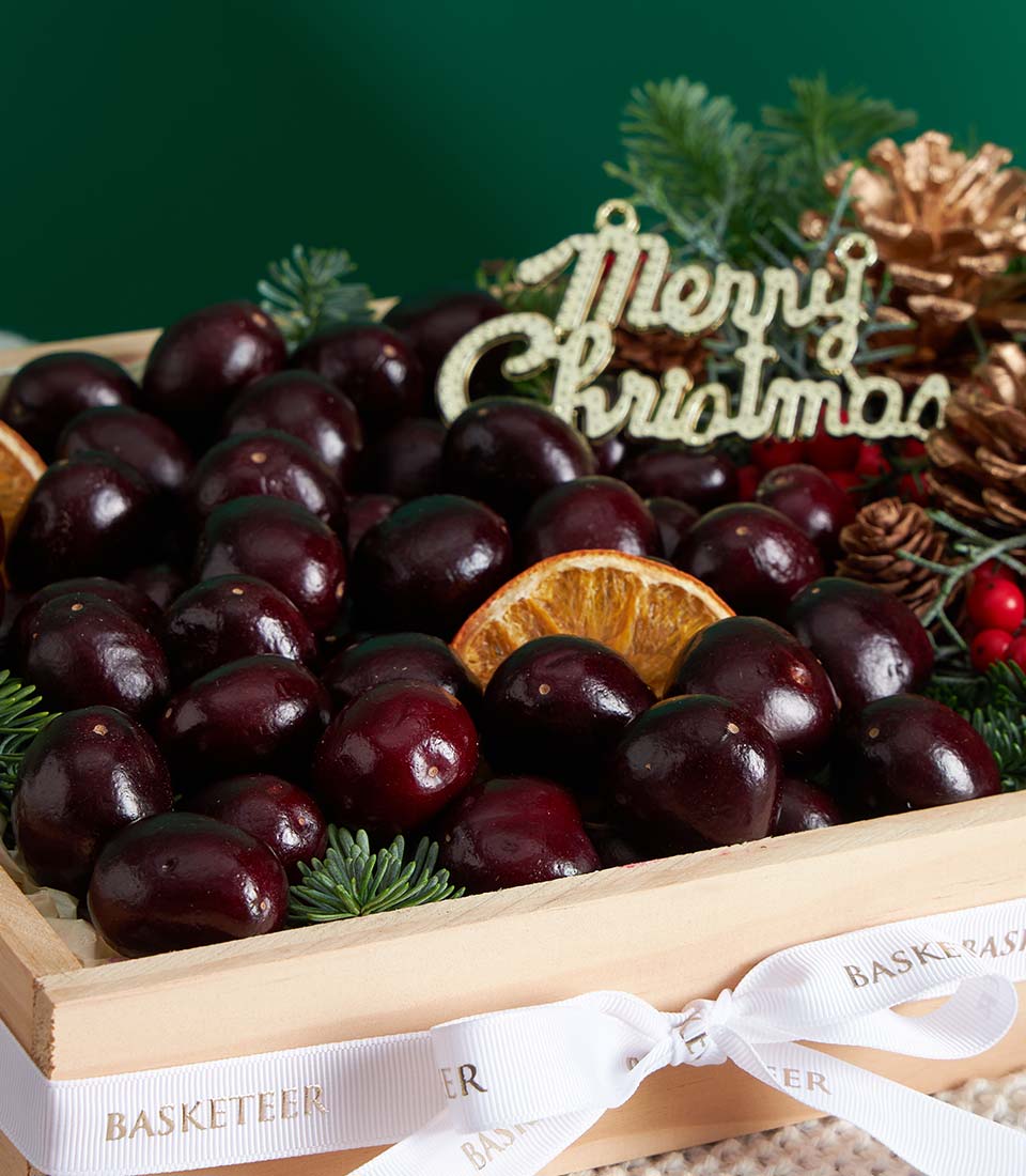 Premium chocolate-covered cherry fruit gift box with dried orange, festive greenery, and gold ribbon for Christmas