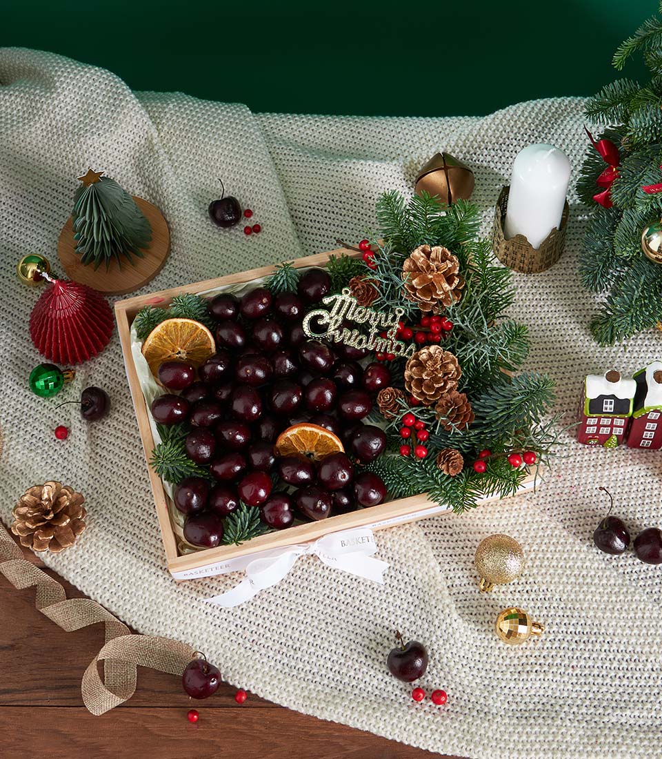 Premium dark red cherries in wooden box with dried citrus and festive greenery, Christmas gift hamper