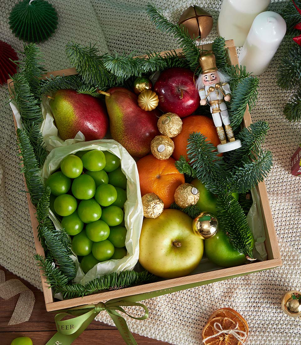 Premium festive fruit and chocolate gift box with fresh pears, apples, oranges, Ferrero Rocher, and gold ornaments