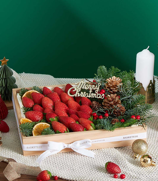 Premium fresh strawberries and dried citrus in wooden Christmas gift box with festive pine and gold accents