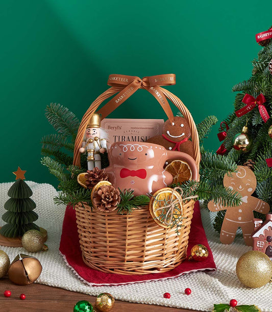 Festive Christmas gift basket with chocolate, shortbread, gingerbread mug, and holiday decorations in wicker with brown