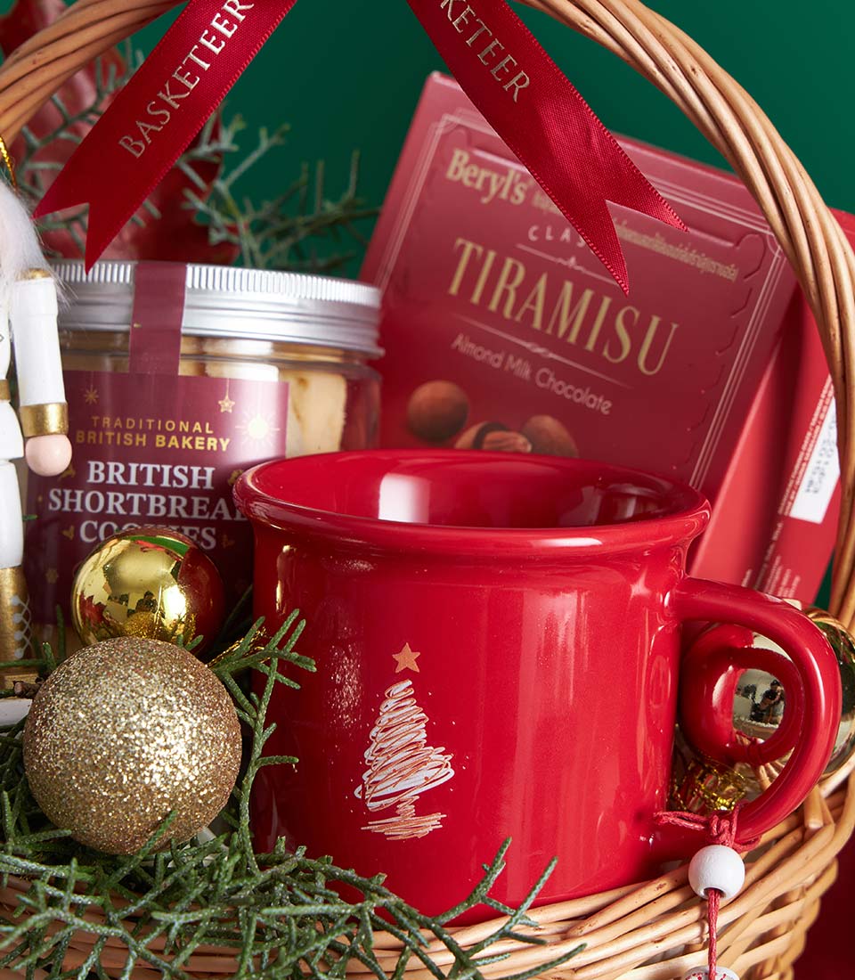 Woven gift basket with gingerbread shortbread, almond chocolate, Christmas mug and festive gold baubles