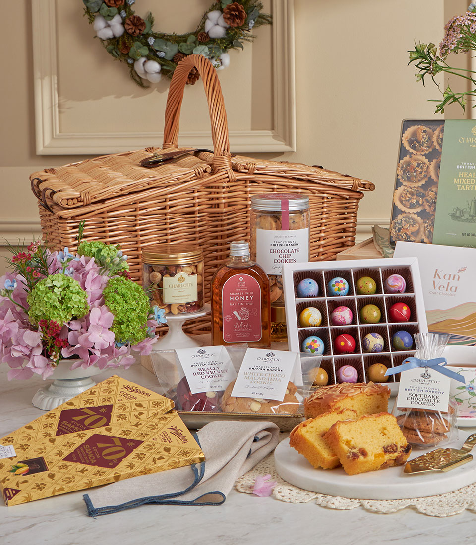 Luxury wicker picnic basket with gourmet chocolates, cookies, honey, fruit cake, and pink hydrangeas for New Year gifting
