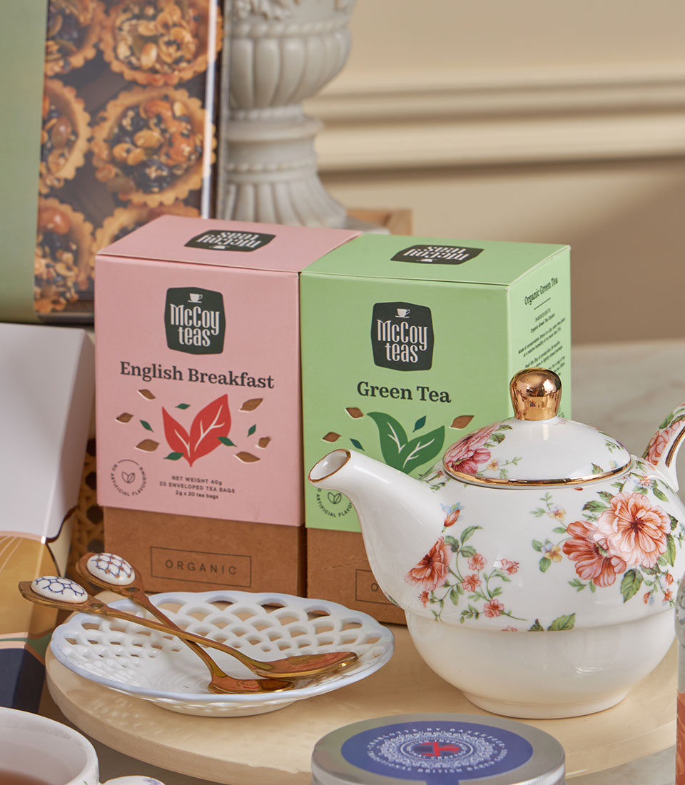 Luxury high tea gift basket with organic McCoy teas, floral ceramic teapot, and gold-trimmed serving pieces for New Year