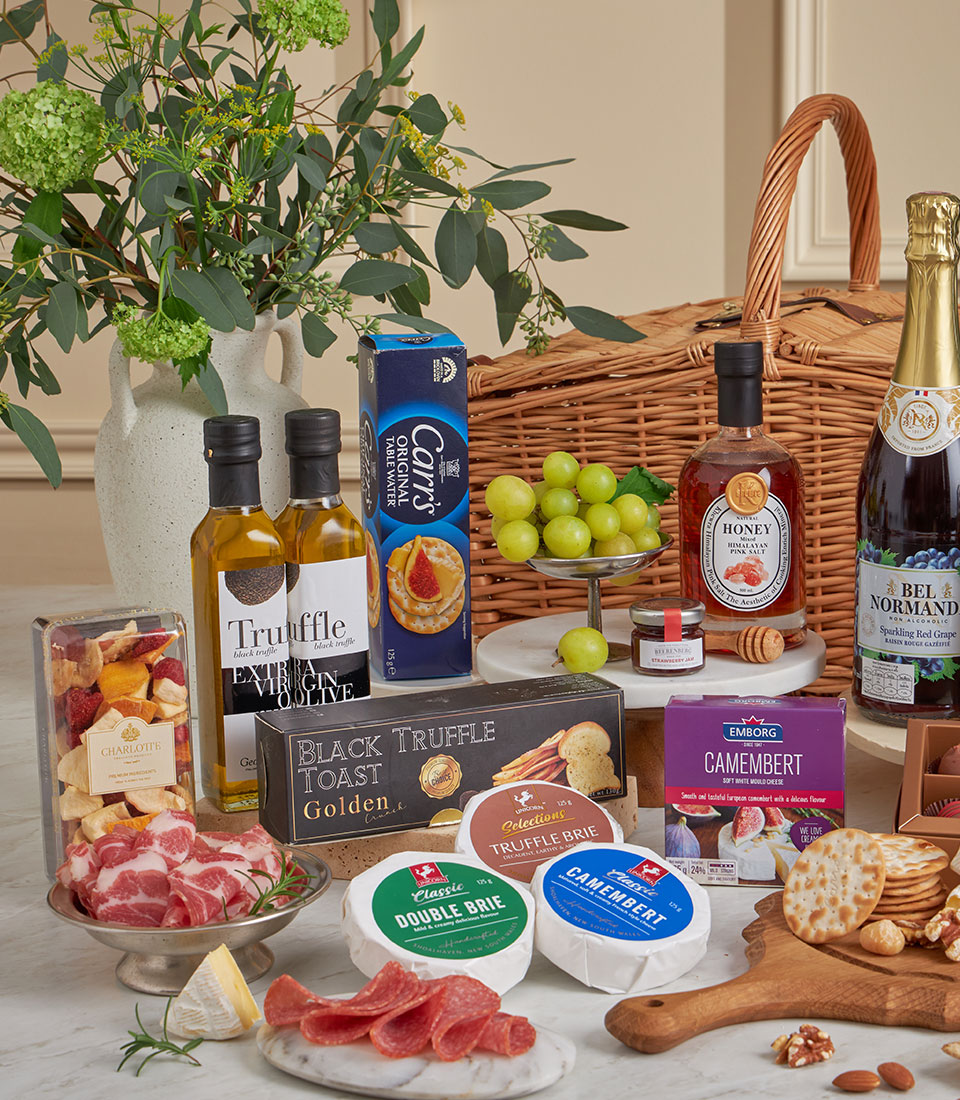 Luxury gourmet gift basket with truffle oil, artisan cheeses, crackers, cured meats, and fresh fruits on marble