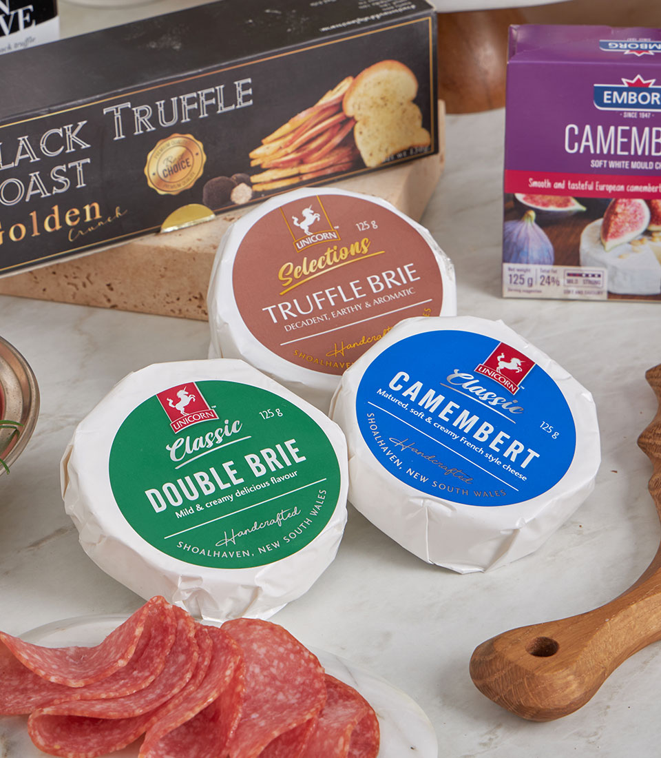 Luxury gourmet cheese gift set with artisan Brie, Camembert, salami, and black truffle crackers on marble
