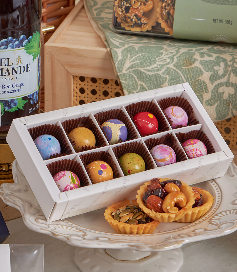 Deluxe Teatime Celebration gift set with colorful gourmet chocolates, nut tarts, and grape beverage on ceramic stand