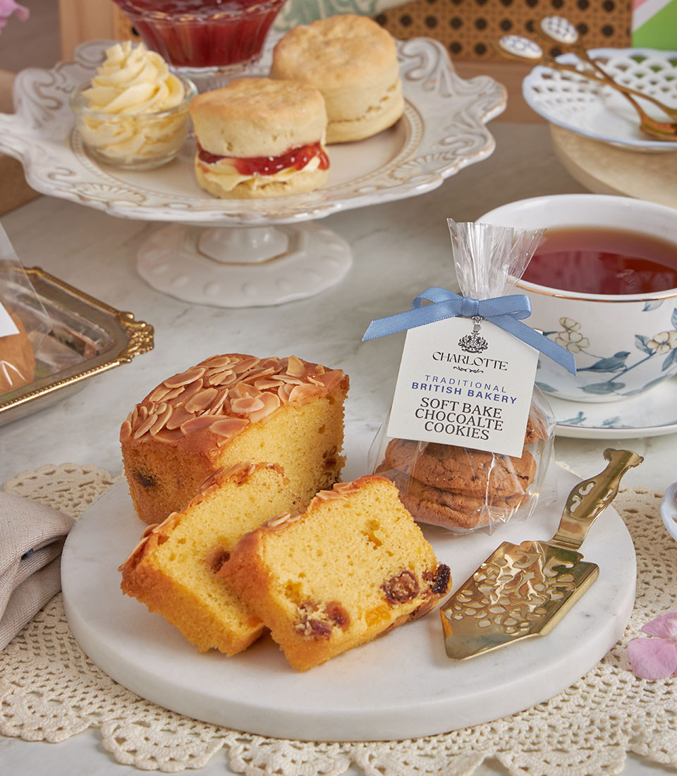 Luxury afternoon tea gift set with almond loaf cake, scones with jam and cream, soft-baked cookies, and blue floral teacup