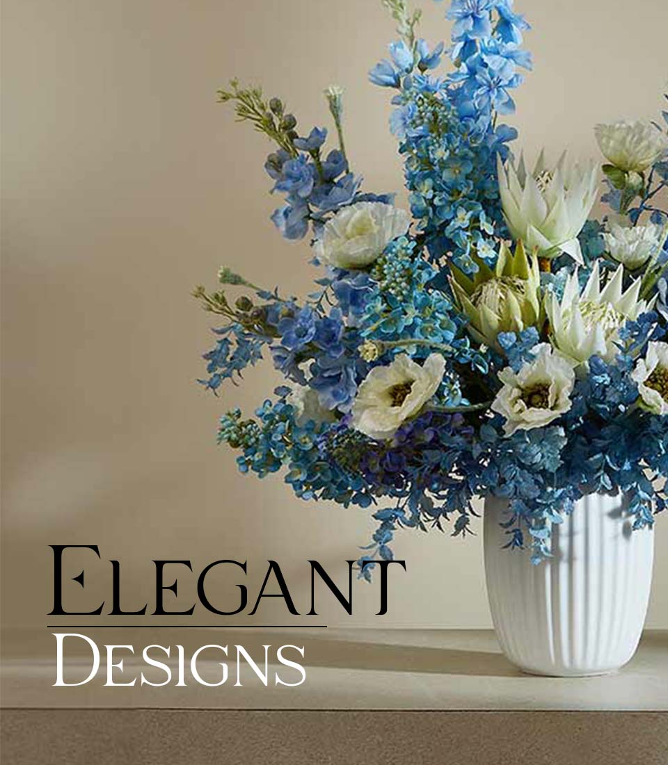 Serenity Blossom artificial flower arrangement in white ceramic vase with blue delphiniums and white proteas