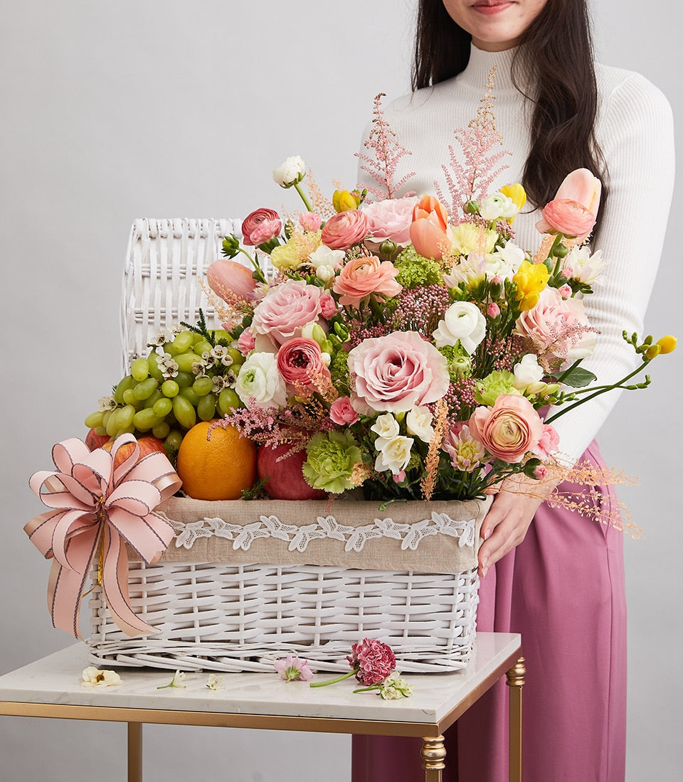 Bright floral fruit basket with pink roses, yellow tulips, fresh fruit and pink ribbon bow