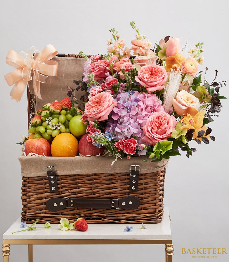 Luxury wicker fruit and flower gift basket with fresh apples, grapes, strawberries, and pink roses